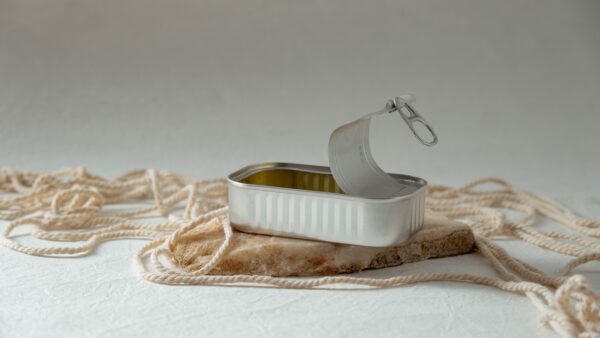 An open tin can lies on a rock slab, surrounded by rope in a studio setting.